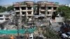 FILE - Afghan municipality workers clean debris in front of the damaged buildings a day after Taliban fighters attacked the offices of a U.-based aid organization in Kabul, May 9, 2019