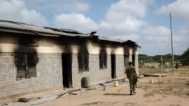 A member of Kenya's security forces walks past a damaged police post after an attack by al-Shabab extremists in the settlement of Kamuthe in Garissa county, Kenya Monday, Jan. 13, 2020
