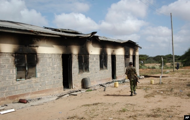 A member of Kenya's security forces walks past a damaged police post after an attack by al-Shabab extremists in the settlement of Kamuthe in Garissa county, Kenya Monday, Jan. 13, 2020