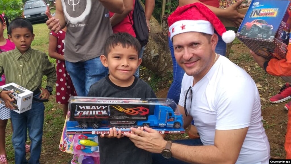 Joel Alvarez gives a Christmas gift to a young boy in northern Panama. Alvarez was part of a group that organized a Christmas celebration last December for 300 people. 