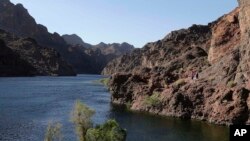 FILE - Hikers make their way along the banks of the Colorado River near Willow Beach, Ariz.