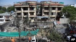 Afghan municipality workers clean debris in front of the damaged buildings a day after Taliban fighters attacked the offices of a U.-based aid organization in Kabul, May 9, 2019