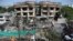 FILE - Afghan municipality workers clean debris in front of the damaged buildings a day after Taliban fighters attacked the offices of a U.-based aid organization in Kabul, May 9, 2019