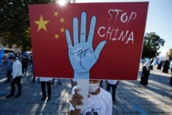 A protester from the Uighur community living in Turkey, holds an anti-China placard during a protest in Istanbul, Oct. 1, 2020.