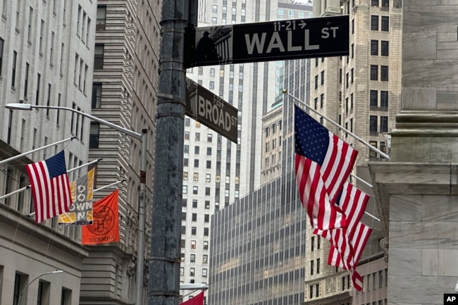 ARCHIVO - Banderas estadounidenses cuelgan de la fachada de la Bolsa de Valores de Nueva York, a la derecha, el 11 de abril de 2024, en Nueva York. (Foto AP/Peter Morgan)