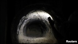 An laborer shines a light into a grave cut into the rock, as construction continues on a new underground cemetery, located at Givat Shaul Cemetery in Jerusalem, Oct. 6, 2019. 