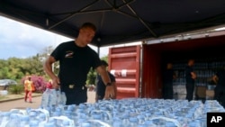 FILE - A security officer picks up water bottles for residents in Tsoundzou, on the French Indian Ocean territory of Mayotte, Saturday Oct. 21, 2023. The crisis is a wakeup call to France about the challenges of managing climate change across France’s far-flung territories.