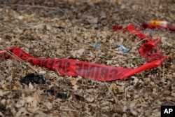 FILE - Police tape litters the ground at the scene of a shooting in Chicago, Ill..
