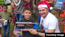 Joel Alvarez gives a Christmas gift to a young boy in northern Panama. Alvarez was part of a group that organized a Christmas celebration last December for 300 people. 