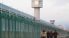 FILE - Workers walk by the perimeter fence of what is officially known as a vocational skills education centre in Dabancheng in Xinjiang Uighur Autonomous Region, China, Sept. 4, 2018. 