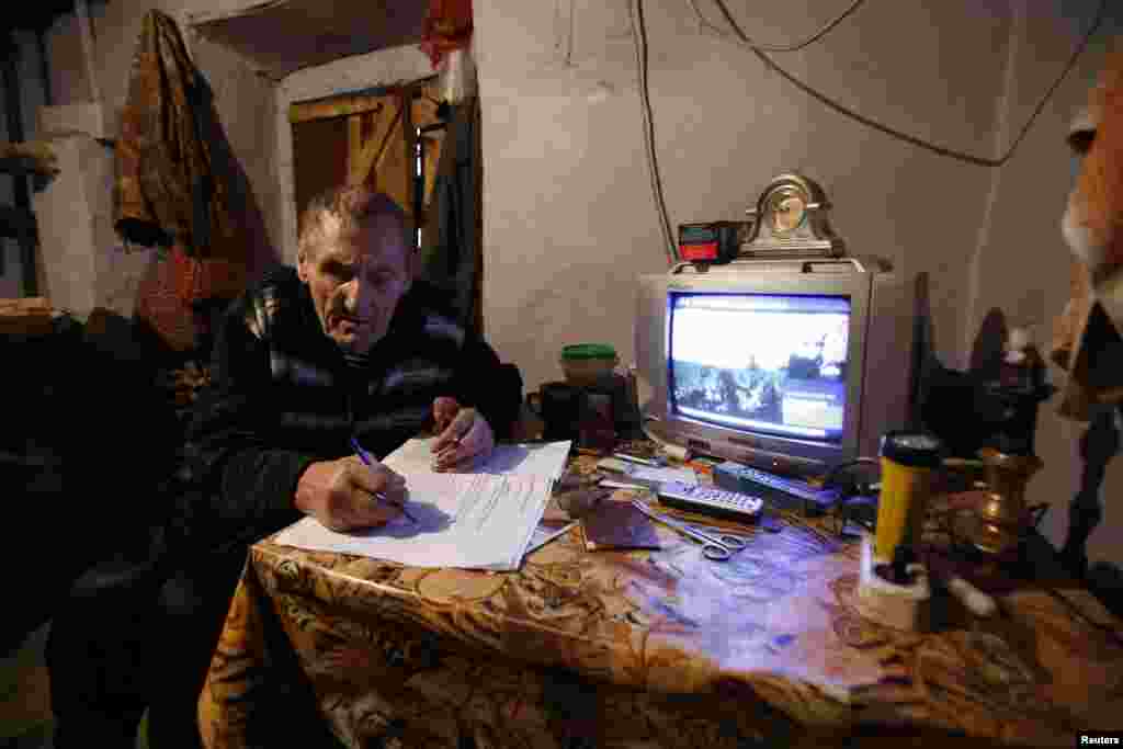 Um homem preenche os papéis de registo antes de descarregar o boletim de voto na urna móvel que ia passar à sua porta, para votar no Referendo na vila de Pionerskoye, perto de Simferopol, Crimeia, Ucrânia, Março 16, 2014. 