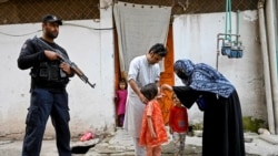 Seorang polisi khusus (kiri) berjaga sementara seorang petugas kesehatan (kanan) memberikan vaksinasi polio kepada seorang anak selama kampanye vaksinasi virus polio di pinggiran kota Peshawar, Pakistan (foto: dok).