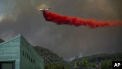 Un avión lanza retardante sobre casas en el área de Basalt, Colorado, el miércoles, 4 de julio de 2018, durante un incendio en Lake Christine.