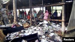 Жители городка Фени смотрят на сгоревшие учебники в школе, где должен был открыться избирательный участок. Почти 60 избирательных участок были сожжены в Бангладеш. 4 января 2014 г.