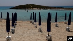 FILE - Rows of closed sun umbrellas are seen on a nearly empty beach in Cyprus' seaside resort of Ayia Napa, a favorite among European and other tourists, May 13, 2020