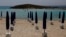 FILE - Rows of closed sun umbrellas are seen on a nearly empty beach in Cyprus' seaside resort of Ayia Napa, a favorite among European and other tourists, May 13, 2020