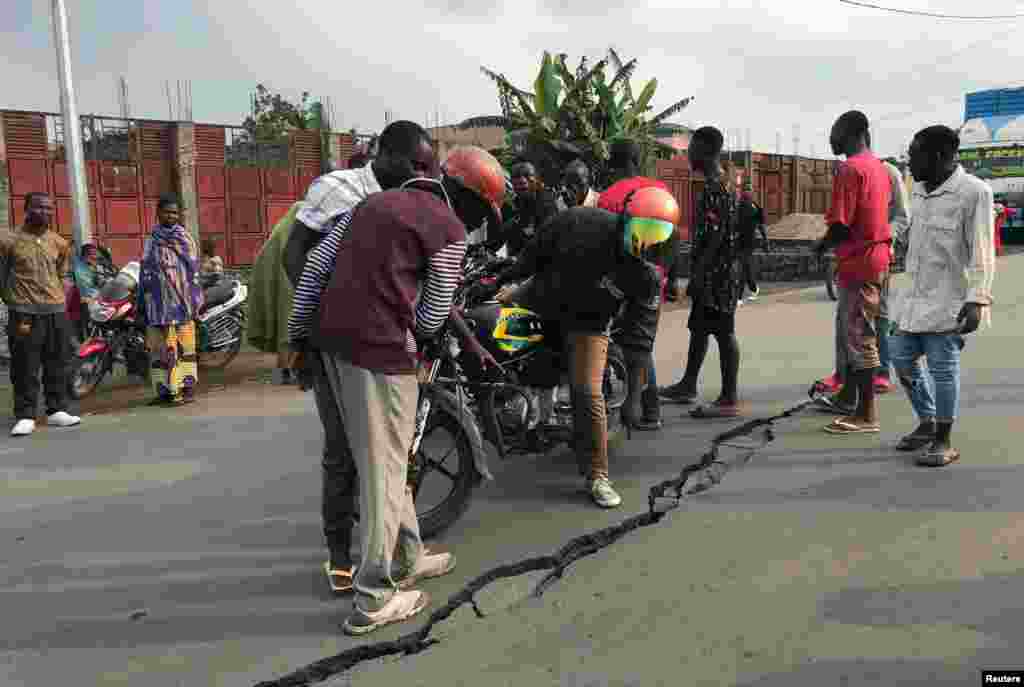 People look at a crack in the road caused by Earth tremors amid aftershocks following the eruption of Mount Nyiragongo volcano near Goma, in the Democratic Republic of Congo.
