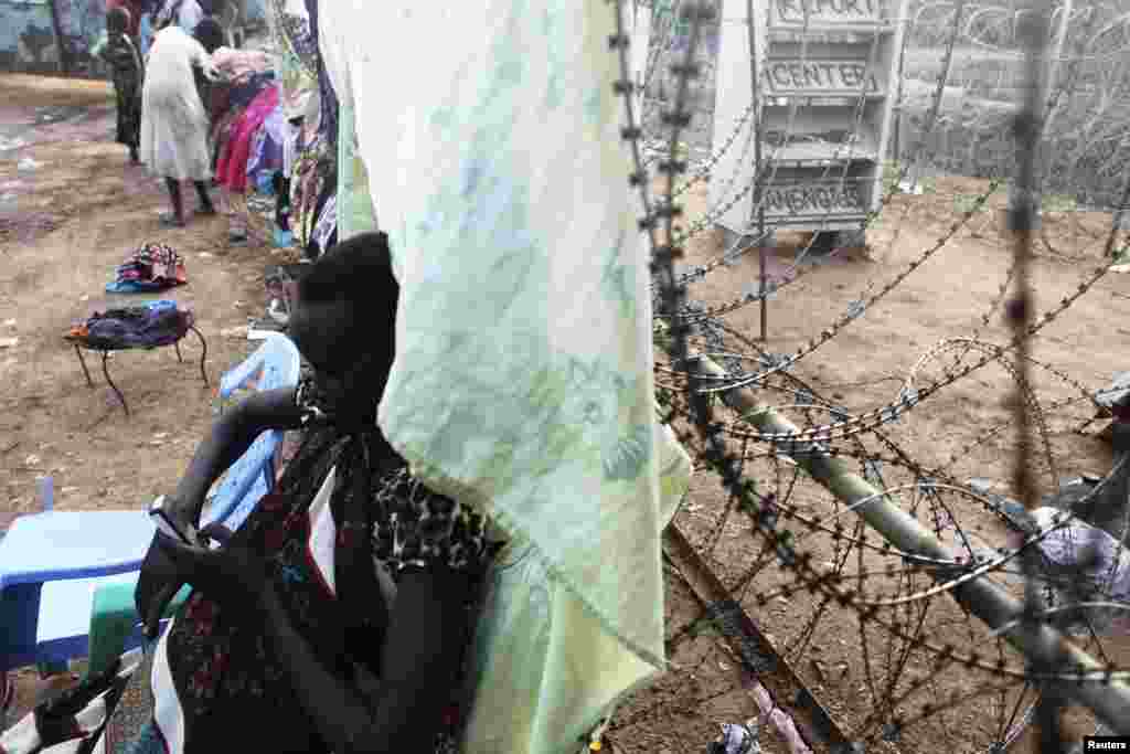Uma mulher sul-sudanesa usa o seu telefone encostada a uma cerca de arame farpado no campo para deslocados no acampamento do UNMISS em Tongping, Juba, Sudão do Sul, Fev. 19, 2014. 