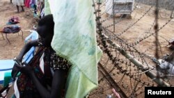 A displaced South Sudanese woman makes a cell phone call at a barbed wire fence in the UNMISS Tongping camp in Juba on February 19, 2014. Thousands are still in the camps, too afraid to go home.