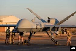 FILE - This photo provided by the French Defense Ministry communication center and taken Tuesday Dec. 17, 2019, shows French soldiers loading a French Reaper drone with two GBU 12 missiles on Niamey airbase, Niger.