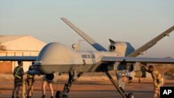 FILE- This photo provided by the French Defense Ministry communication center and taken Tuesday Dec. 17, 2019, shows French soldiers loading a French Reaper drone with two GBU 12 missiles on Niamey airbase, Niger. 