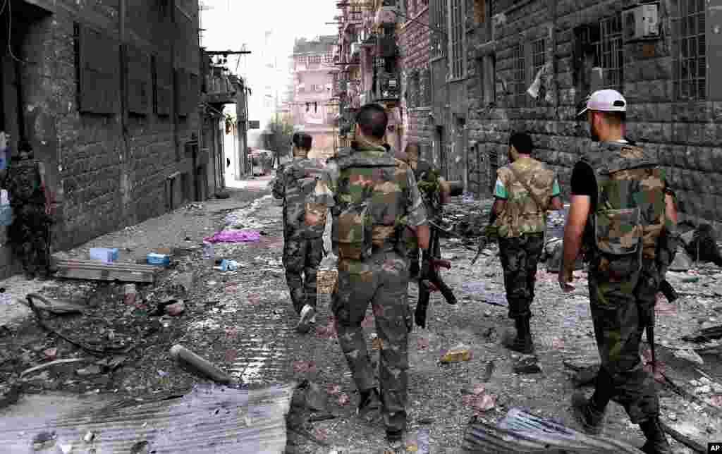 In this photo released by the Syrian official news agency SANA, Syrian government forces patrol the damaged area of the al-Arqoub district in Aleppo, Syria, Sept. 24, 2012.