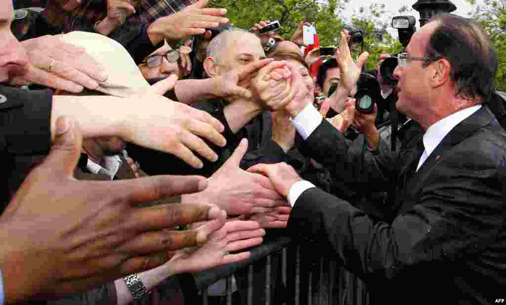 France's new President Hollande shakes hands with supporters on the Champs Elysees Avenue after the handover ceremony in Paris May 15, 2012. (Reuters)