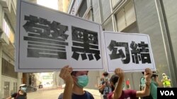 兩名年輕人7月19日下午在元朗西鐵站附近高舉抗議警方的大型標語，他們一度被警方截查。（美國之音湯惠芸）