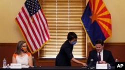 Sekretaris Daerah dari Partai Demokrat Katie Hobbs (kiri) memperhatikan Direktur Pemilu, Bo Dul, memberi Gubernur Arizona Doug Ducey dokumen hasil pilpres, Senin, 30 November 2020 di Phoenix.