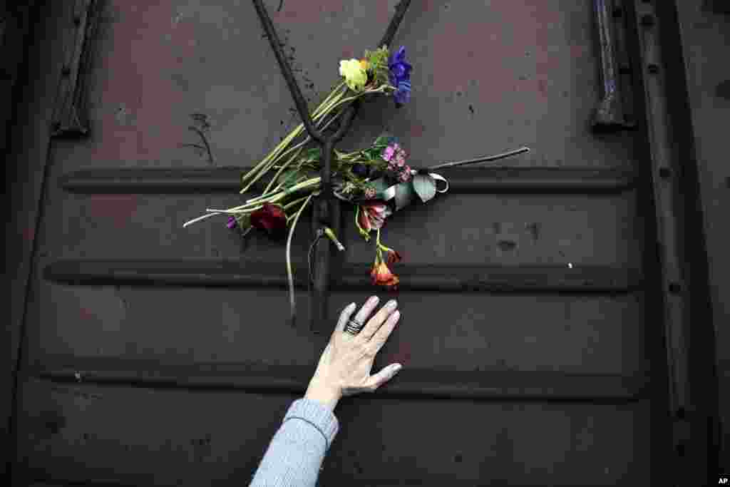 A woman places flowers on a train wagon at the old train station in Thessaloniki, Greece, to mark the 74th anniversary of the roundup and deportation of its Jews to Nazi extermination camps during World War II.