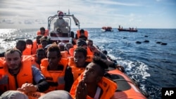 ربڑ کی کشتی میں جان بچا کر فرار ہونے والے پناہ گزینوں کو اسپین کے ایک غیر سرکاری ادارے پرو ایکٹو اوپن آرمز کے رضا کاروں نے بحیرہ روم میں لیبیا کے ساحل سے پینتالیس میل دور ڈوبنے سے بچایا ۔ فائل فوٹو اے پی 