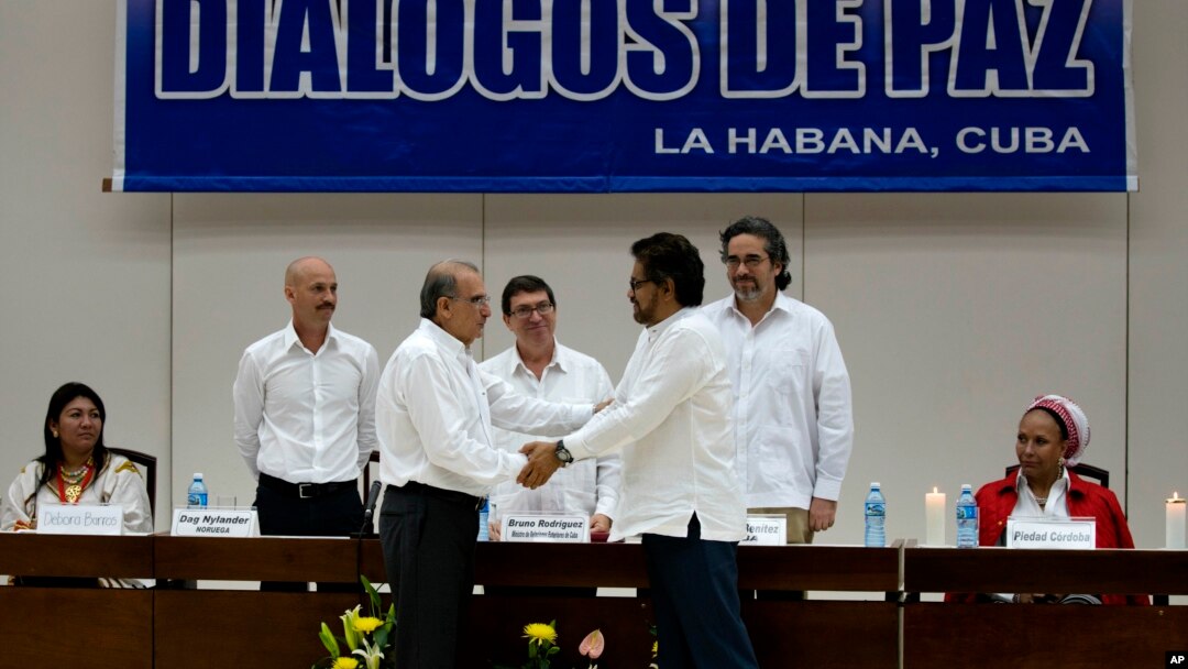 Wakil pemerintah Kolombia, Humberto de la Calle (kiri) berjabat tangan dengan Ivan Marquez, wakil dari pemberontak FARC, setelah menyepakati perjanjian ganti rugi korban perang di Havana, Kuba, Selasa (15/12). 