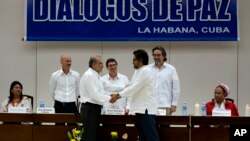 Wakil pemerintah Kolombia, Humberto de la Calle (kiri) berjabat tangan dengan Ivan Marquez, wakil dari pemberontak FARC, setelah menyepakati perjanjian ganti rugi korban perang di Havana, Kuba, Selasa (15/12). 