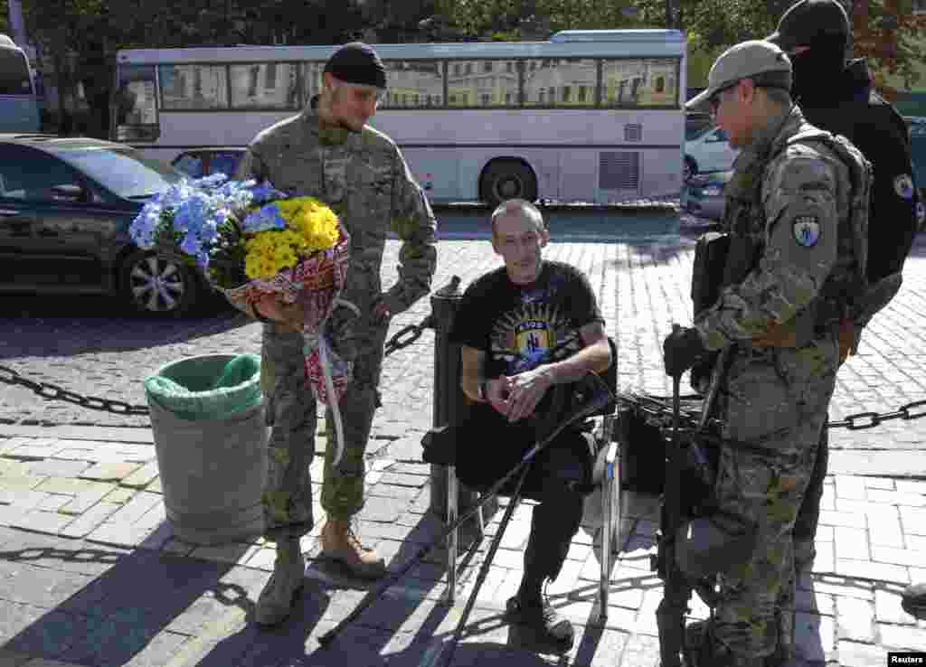 Volunteers, who returned from the front line in the eastern regions of Ukraine, talk to their friend injured earlier during fighting with pro-Russian separatists in the east of Ukraine, in Kyiv, Sept. 15, 2014.