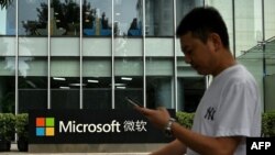 Un hombre usa su teléfono móvil mientras camina frente a la sede local de Microsoft en Beijing el 20 de julio de 2021, un día después de que Estados Unidos acusó a Beijing de llevar a cabo el ataque cibernético contra Microsoft.