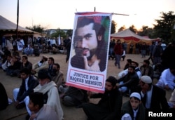 FILE - A member of the Pashtun community holds a picture of Naqibullah Mehsud, whose extrajudicial killing by Karachi police sparked nationwide protests, in Islamabad, Pakistan, Feb. 1, 2018.
