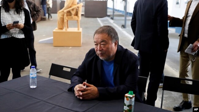 Dissident Chinese artist Ai Weiwei sits at a table at the end of a news conference during a press preview of his new exhibition