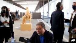 Dissident Chinese artist Ai Weiwei sits at a table at the end of a news conference during a press preview of his new exhibition "Rapture" in Lisbon, Thursday, June 3, 2021.