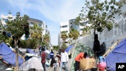 FILE— Migrants walk in a makeshift camp outside the International Organization for Migration office, March 31, 2023 in Tunis. 