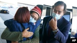 Danny Fenster, center, hugs his mother Rose Fenster as former U.S. diplomat Bill Richardson, right, looks on at John F. Kennedy Airport in New York, Nov. 16, 2021.