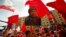 FILE - A supporter of Venezuela's President Nicolas Maduro holds up a picture of late president Hugo Chavez during a May Day demonstration in Caracas, May 1, 2014. 