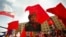 FILE - A supporter of Venezuela's President Nicolas Maduro holds up a picture of late president Hugo Chavez during a May Day demonstration in Caracas, May 1, 2014. 