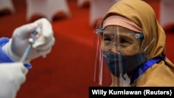 Seorang perempuan bersiap menerima suntikan vaksin Sinovac selama program vaksinasi massal di Bursa Efek Indonesia di Jakarta. (Foto: REUTERS/Willy Kur