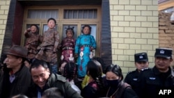 children in traditional Tibetan clothes and police watching passing Tibetan Buddhist monks 2010