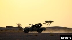 FILE - The Polisario Front soldiers drive a pick-up truck mounted with an anti-aircraft weapon at sunset in Bir Lahlou, Western Sahara, Sept 9, 2016. 