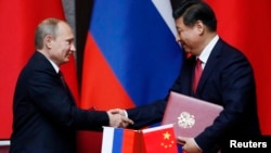 Russia's President Vladimir Putin (L) and China's President Xi Jinping shake hands after signing an agreement during a bilateral meeting at the Xijiao State Guesthouse ahead of the fourth Conference on Interaction and Confidence Building Measures in Asia 