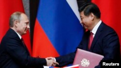 Tổng thống Nga Vladimir Putin (trái) và Chủ tịch Trung Quốc Tập Cận Bình bắt tay sau khi ký kết một thỏa thuận 20/5/14