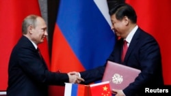 Presiden Rusia Vladimir Putin (kiri) dan Presiden China Xi Jinping berjabat tangan seusai penandatangan perjanjian bilateral di Shanghai (20/5).