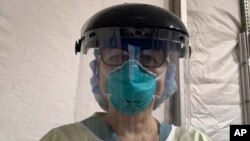 Tuesday, March 31, 2020 photo provided by emergency room nurse Cynthia Riemer shows her at the University of Illinois Hospital in Chicago, wearing a welder’s mask from a hardware store and other hospital-issued protective gear. 