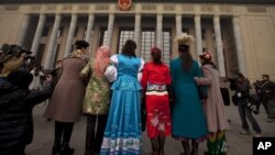 Uighur ethnic minority delegates in their traditional dresses pose for photos as they walk towards the Great Hall of the People for the opening session of the annual National People's Congress in Beijing, China, March 5, 2012. 